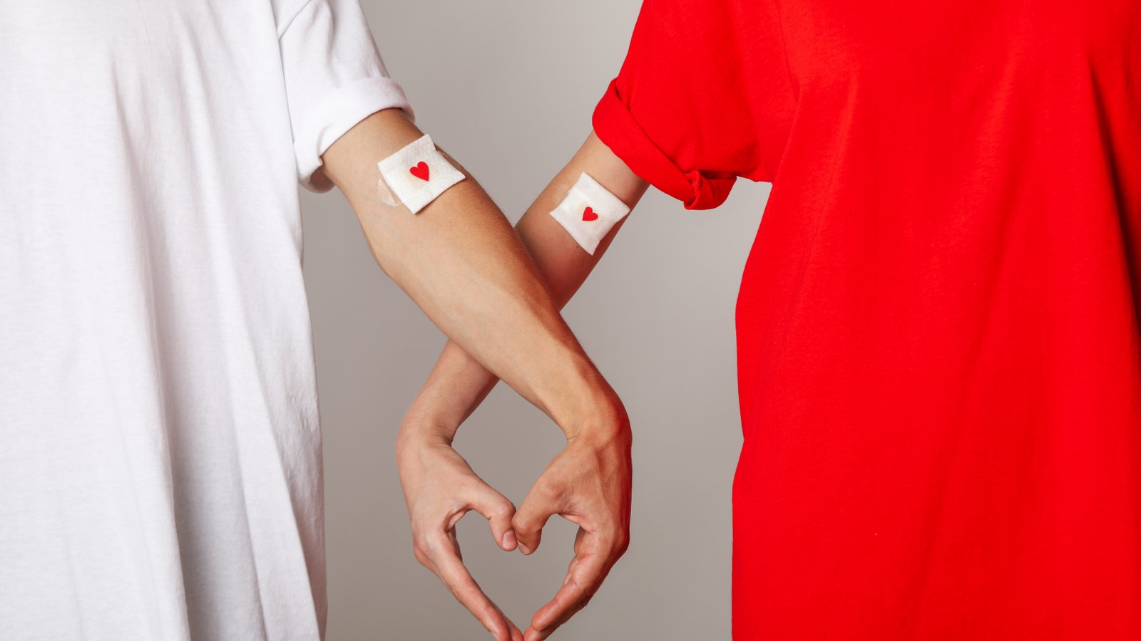 Dos personas con vendajes de donación formando corazón con las manos